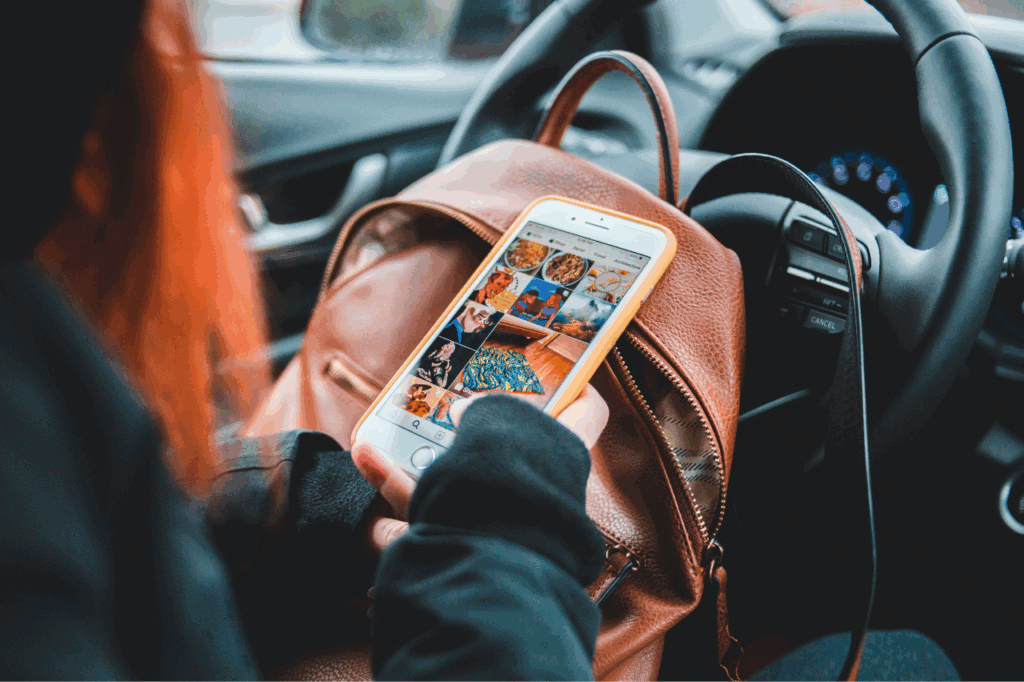 Woman in stationary car checking social media.