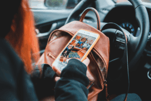 Woman in stationary car checking social media.