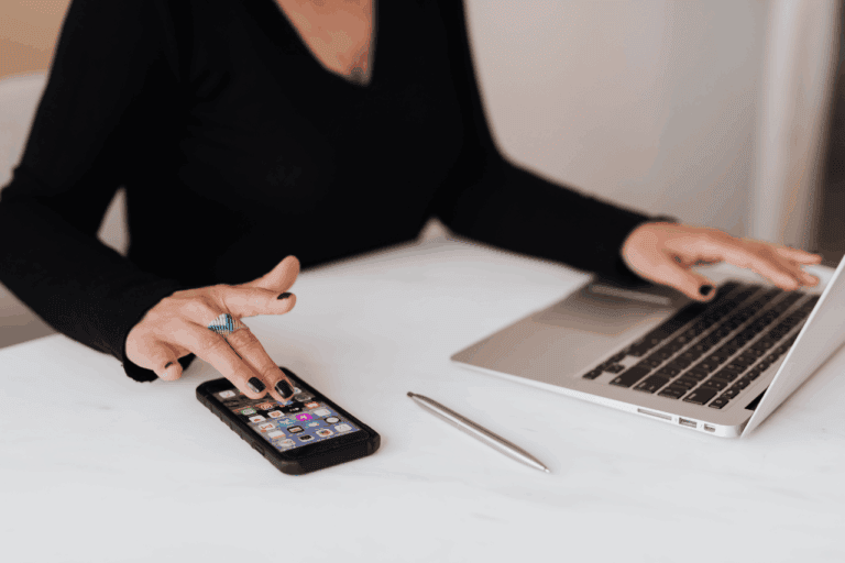 Woman typing on laptop and phone simultaneously to symbolise checking SEO growth.
