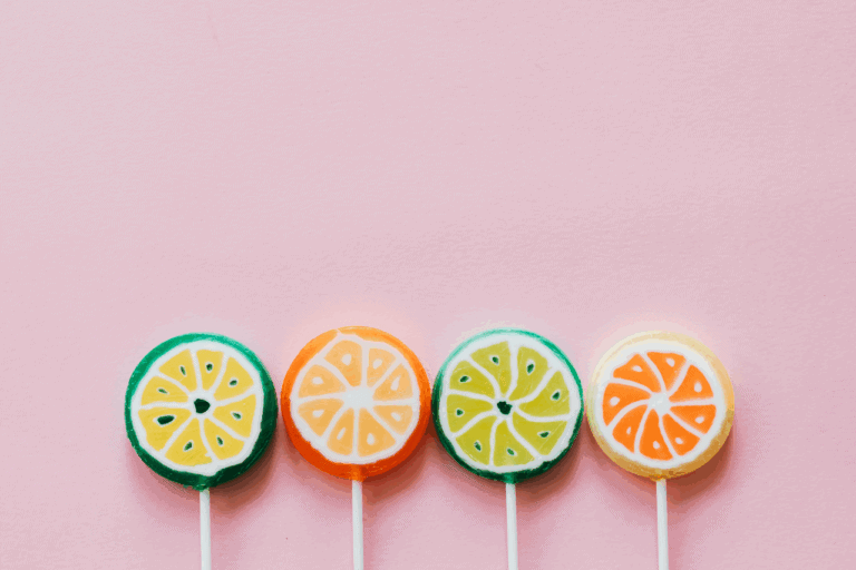Different coloured fruit lollies against a pink background to represent choice