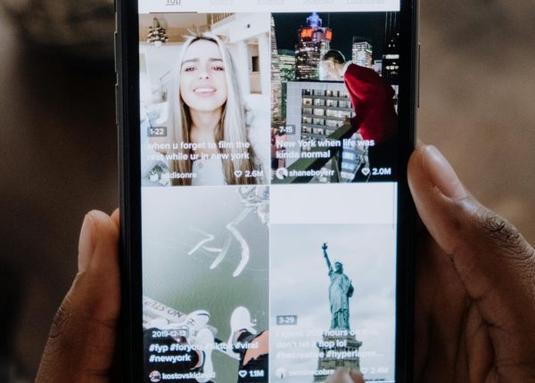 Close-up of a person using a smartphone to browse a social media app indoors.